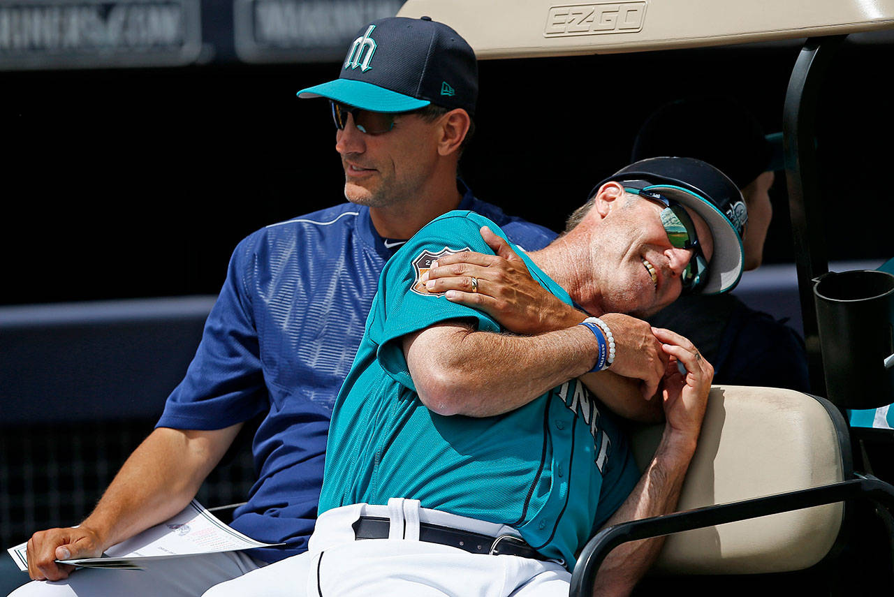 Mariners first base coach Casey Candaele (right) gets a playful hug from bench coach Tim Bogar prior to a spring training game on March 25, 2017, in Peoria, Ariz. (AP Photo/Ross D. Franklin)