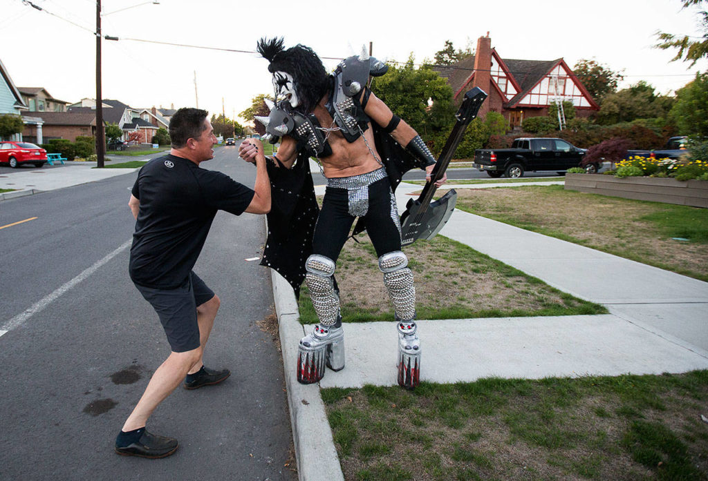 Dressed up as Gene Simmons of KISS fame, Everett paramedic Jack Murrin and neighbor John Tanaka greet each other out on the street as Murrin heads out to a open mic session at Cafe Zippy on Oct. 7 in Everett. (Andy Bronson / The Herald)

