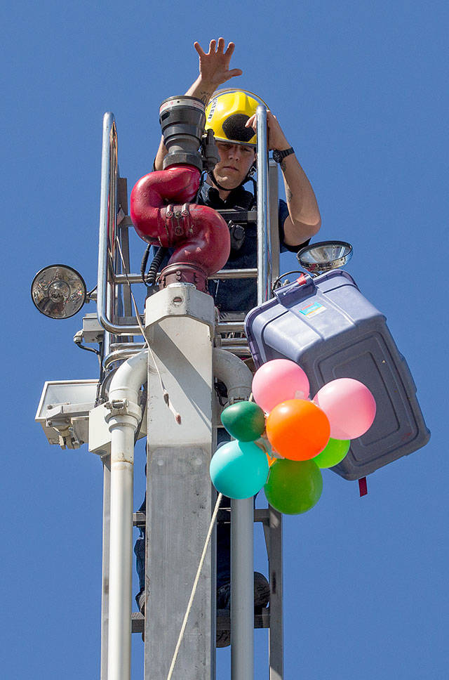 Snohomish County firefighter Colin Nash drops one of nearly 100 “landing crafts,” protecting a raw egg, from a 70-foot drop from the top of a ladder truck at Dutch Hill Elementary on Thursday in Snohomish. Student used various items a techniques to try and keep a egg from breaking from the drop. (Andy Bronson / The Herald)