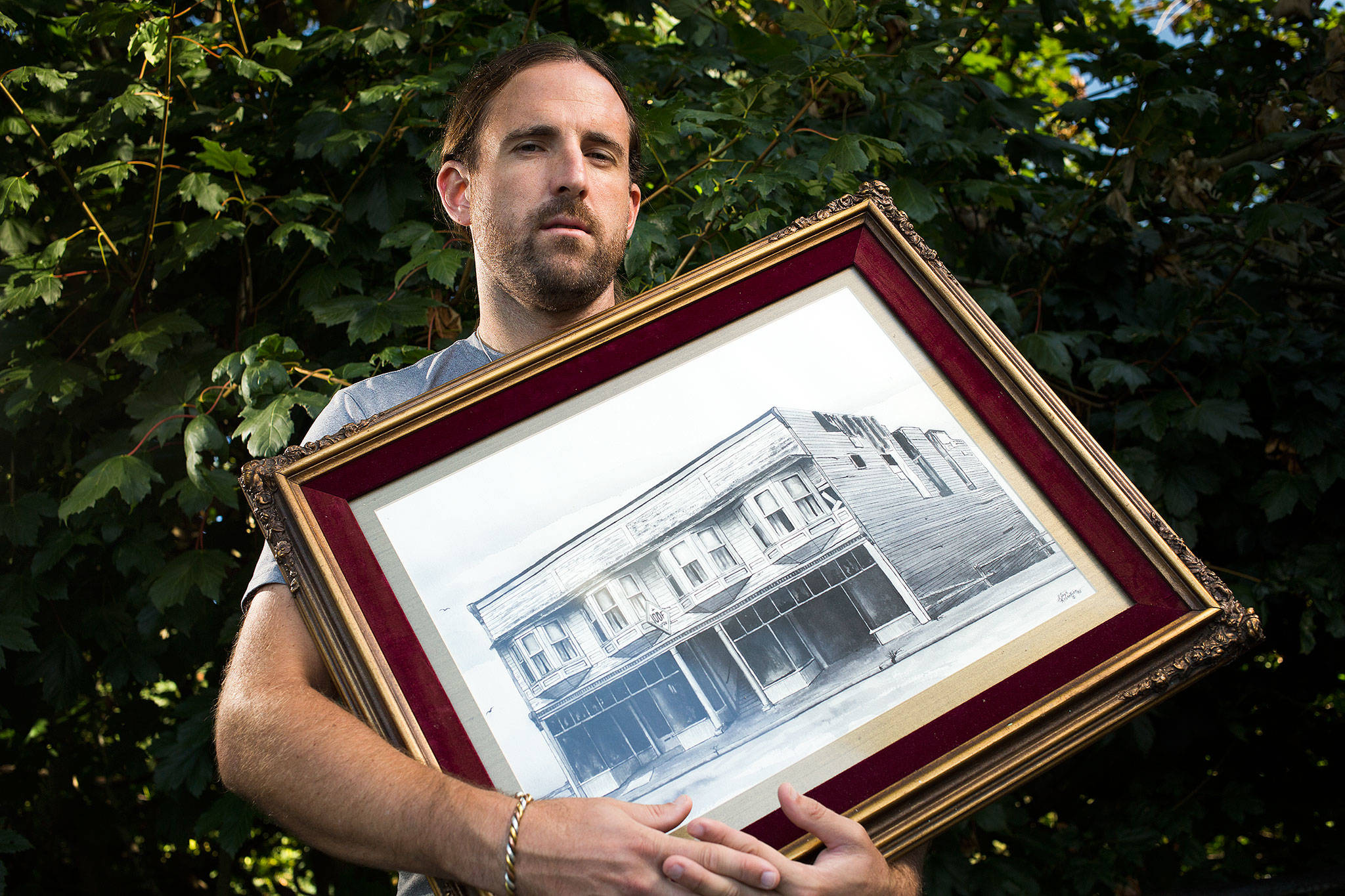 Jeremy Jones, owner of the Everett Office Furniture property that burned to the ground, holds a drawing of it Oct. 9 in Edmonds. More than 115 years of local history was burned to the ground. (Andy Bronson / The Herald)