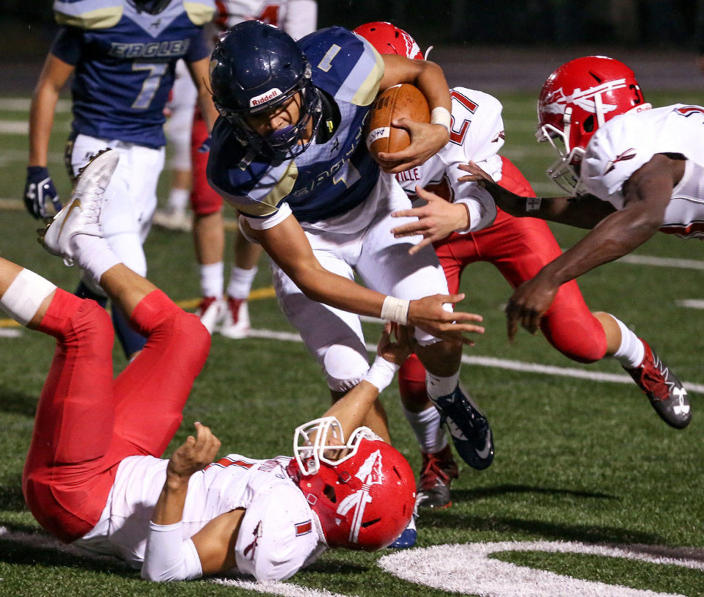 Arlington’s Tallen Williams carries the ball against the Marysville Pilchuck defense during a game Oct. 6, 2017, at Arlington High School. (Kevin Clark / The Herald)
