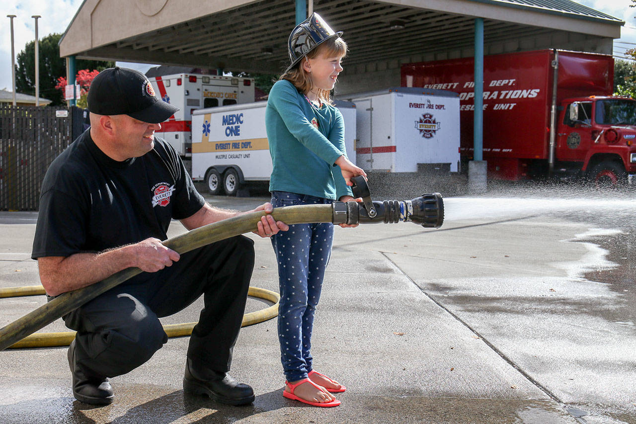 Mike Goforth carries the weight of the hose as Grace Yanasak directs the spray Sunday morning at Fire Station 1 in Everett. (Kevin Clark / The Herald)