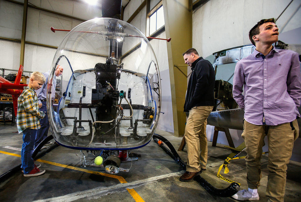 Paul Laycock, 7 (left), Garret Lengyel, (back left), Keith Laycock and Philip Laycock, 14, look at aircraft at the EvCC Aviation Maintenance Technology School while waiting for the 50-year anniversary celebration to begin Wednesday. (Dan Bates / The Herald)
