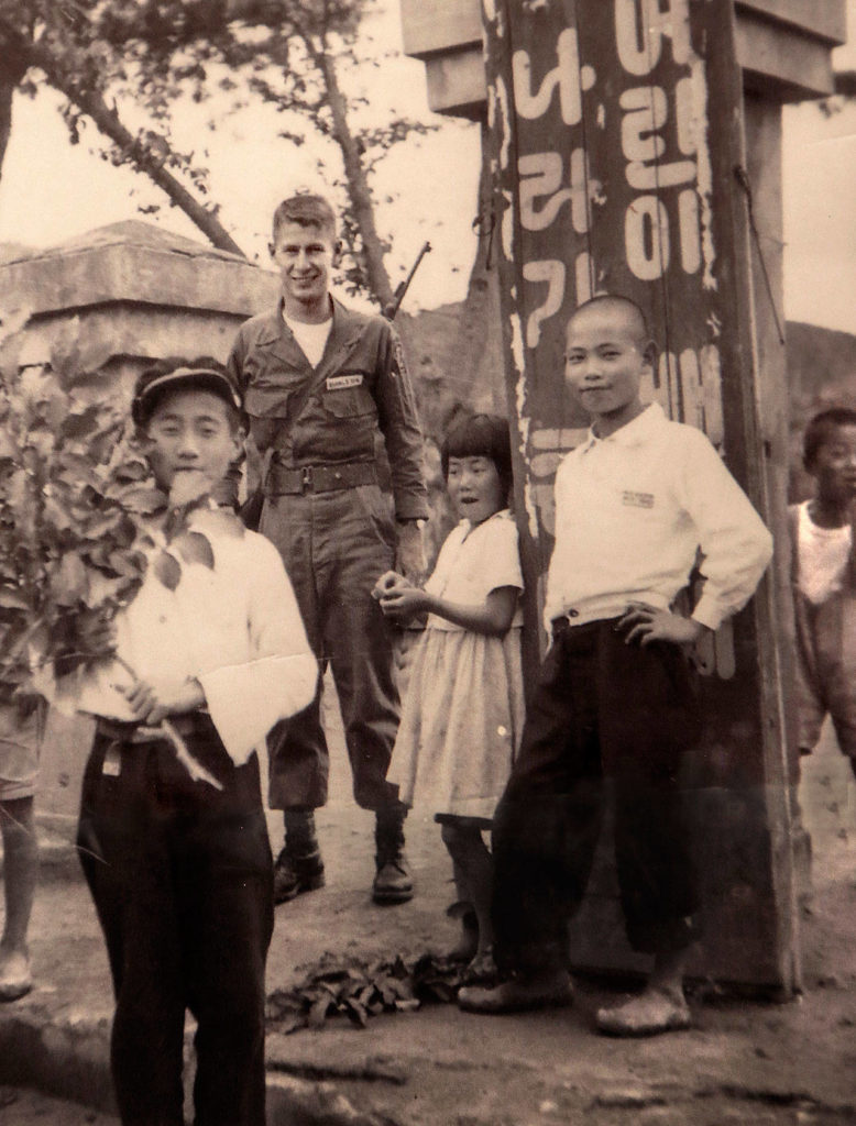 When the fighting stopped a month or so after Gerald Rogers got to the Korean War, he stayed on another year. Here, he was photographed with local children.
