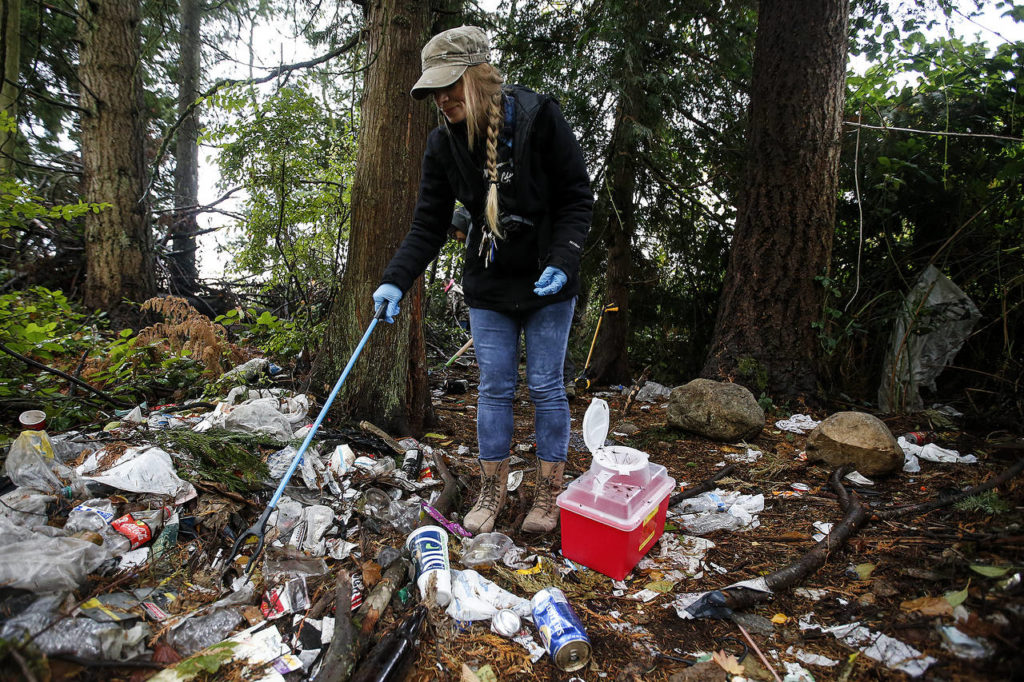 Casey Flagg picks through garbage looking for hypodermic needles to dispose of . (Ian Terry / The Herald)
