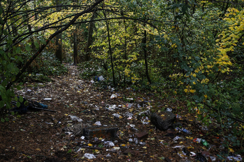 Trash is strewn across a trail in the woods behind Home Depot on Evergreen Way in Everett on Friday. (Ian Terry / The Herald)
