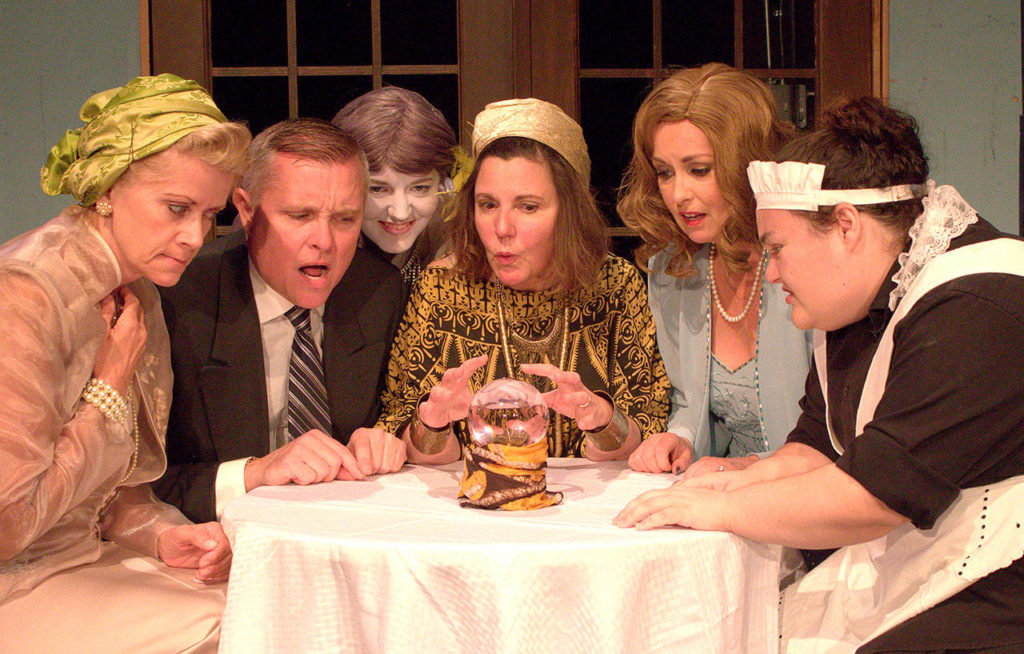 The household gathers for an amusing seance during which Charles’ deceased first wife is unwittingly conjured up in Red Curtain’s production of “Blithe Spirit.” The cast includes, from left, Danette Meline (Mrs. Bradman), Robert Ian Stratton (Charles Condomine), Melanie Stagner (Elvira), Jeannine Early (Madame Arcati), Brianne Green (Ruth Condomine) and Gilly Kelleher (Edith). (Peter Eartheart photo)
