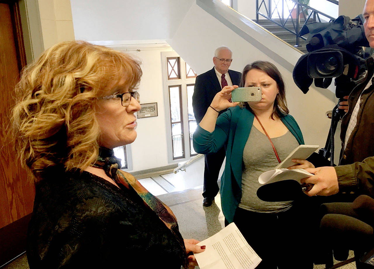 Diane Fox addresses reporters as Skagit County Prosecutor Rich Weyrich (right, in suit) watches on Thursday in Mount Vernon. Fox accused Weyrich of grandstanding by alerting news organizations to efforts by her son, Steven Rickards, to seal records of his juvenile court conviction for murdering his 8-year-old sister in 2001. (AP Photo/Gene Johnson)