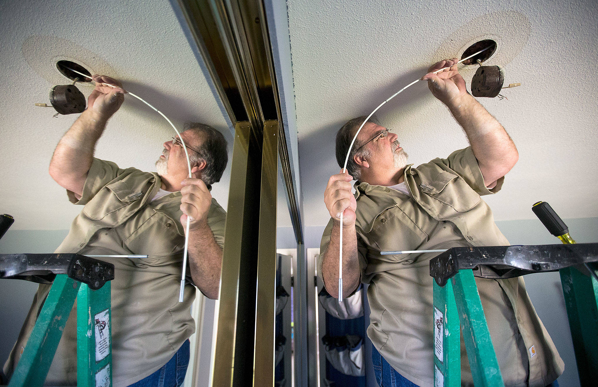 Don Thomas of RD Handyman Service installs a ceiling fan at a home in southeast Everett. (Andy Bronson / The Herald)