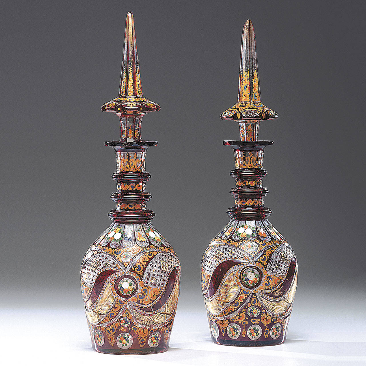 These 19th-century Bohemian flashed glass decanters were blown, flashed with red glass, cut, and then decorated with orange and black enamel and gilt. The 20-inch-high pair auctioned for $1,920. (Cowles Syndicate Inc.)