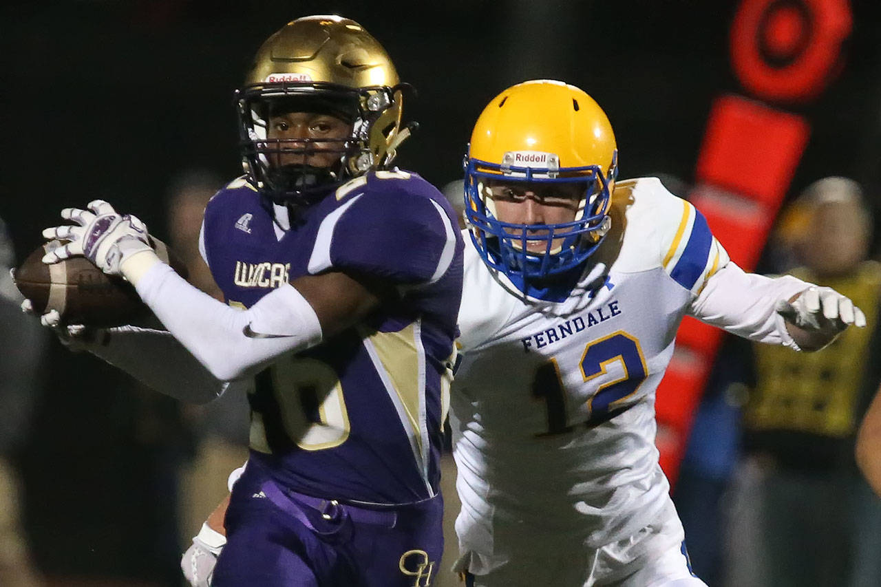 Oak Harbor’s Tamarik Hollins-Passmore hauls in a reception with Ferndale’s Jared Emmert trailing during a game Oct. 13, 2017, at Oak Harbor High School. (Kevin Clark / The Herald)