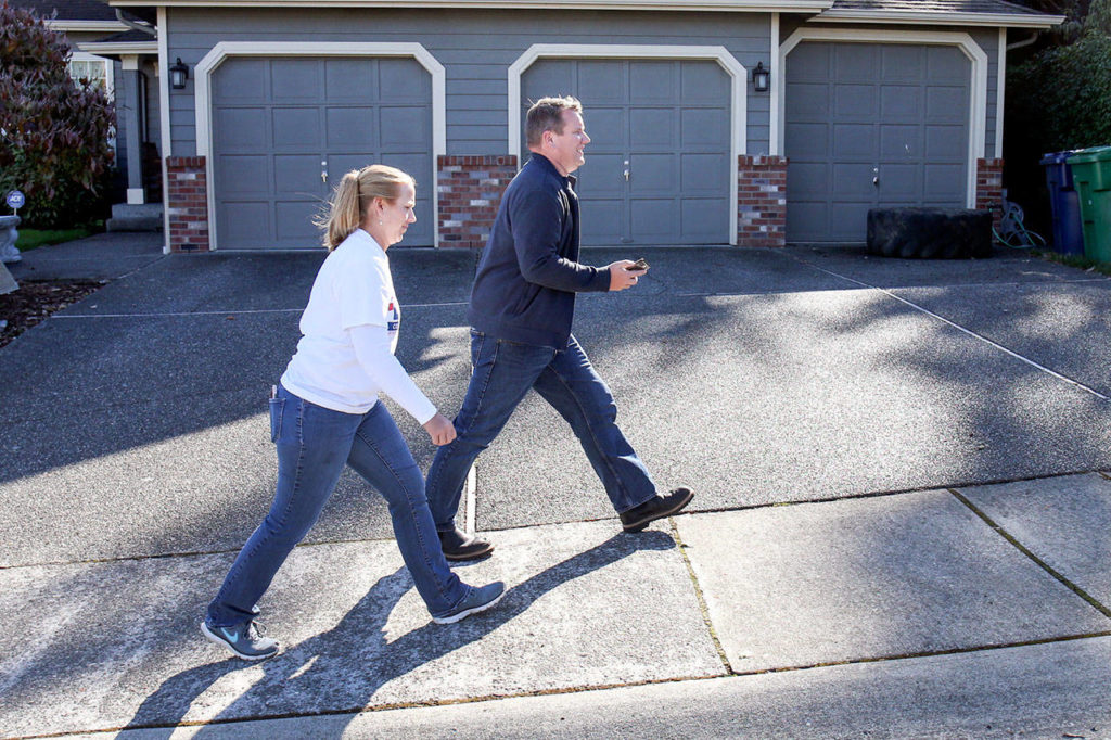 Mariah Low (left), along with Sam Low go door-to-door Sunday afternoon in unincorporated Everett. (Kevin Clark / The Herald)
