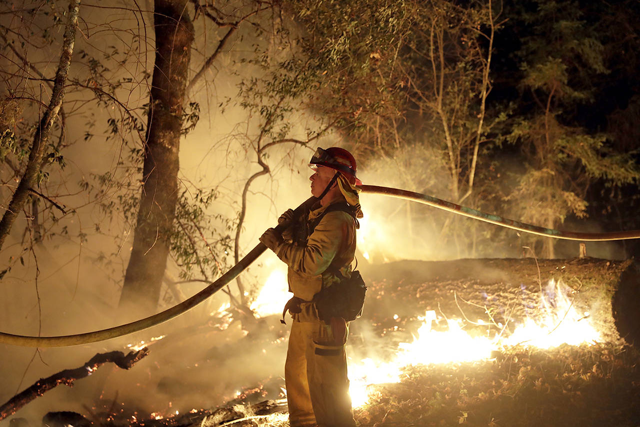 A firefighter holds a water hose while fighting a wildfire Saturday in Santa Rosa, California. (AP Photo/Marcio Jose Sanchez)