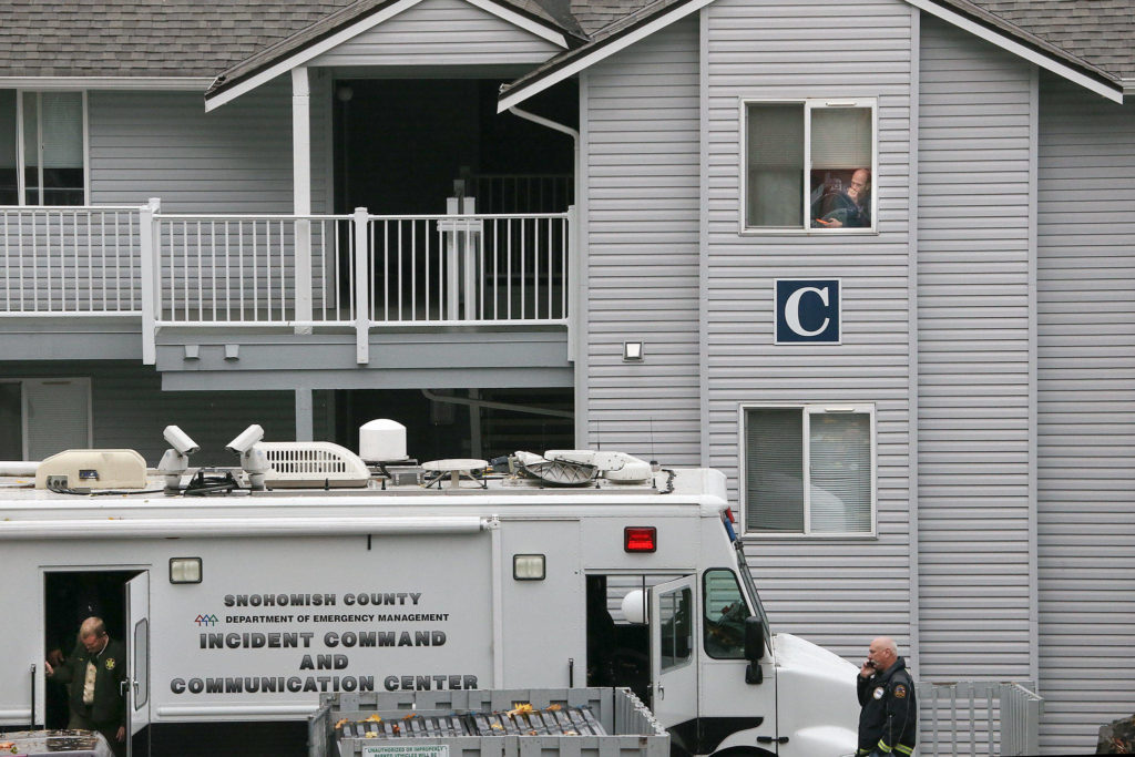 A man looks out from a third floor window as investigators collect evidence, where a boy’s body was found in a dumpster, at Bristol Square Apartments on Tuesday in Lynnwood. (Andy Bronson / The Herald)

