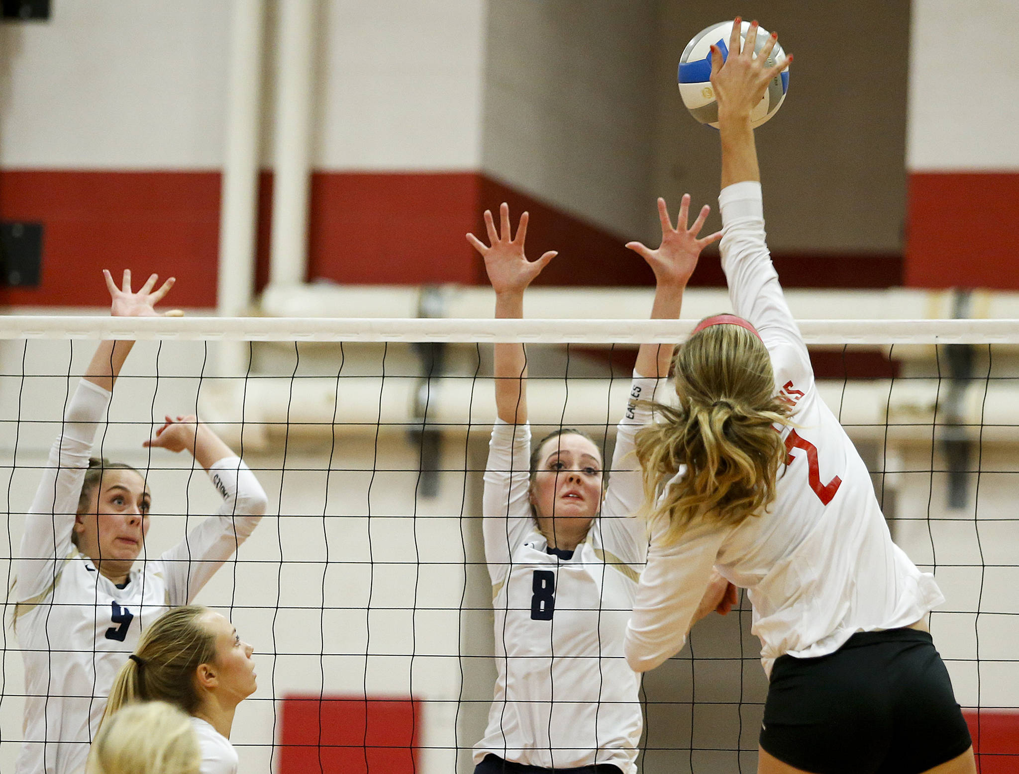 Stanwood’s Jillian Heichel (2) spikes a ball as Arlington’s Sarah Mekelburg (9) and Reese Talbot (8) defend during Tuesday’s match at Stanwood High School. (Ian Terry / The Herald)