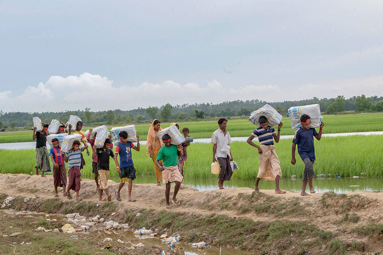 Rohingya Muslim volunteers, who crossed over from Myanmar into Bangladesh, carry food and plastic sheets for stranded refugees at Palong Khali, Bangladesh, on Wednesday. (AP Photo/Dar Yasin)