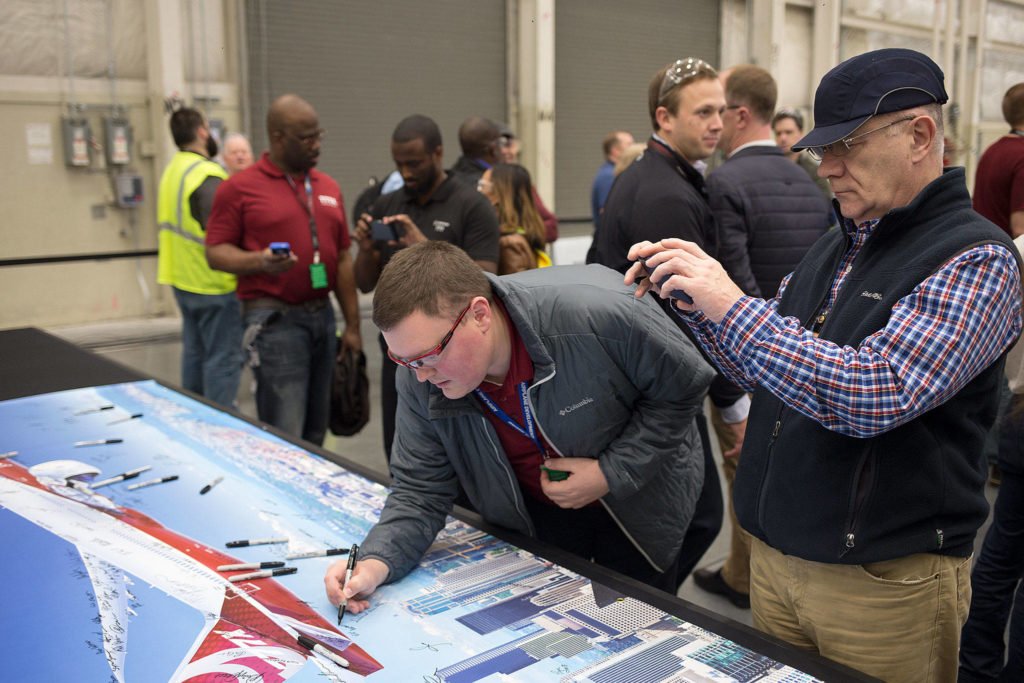 Boeing employees sign and take photos of a poster bearing an image of the new 777X while attending a gala at the composite wing center on Monday. (Dave Rzegocki / For the Herald)
