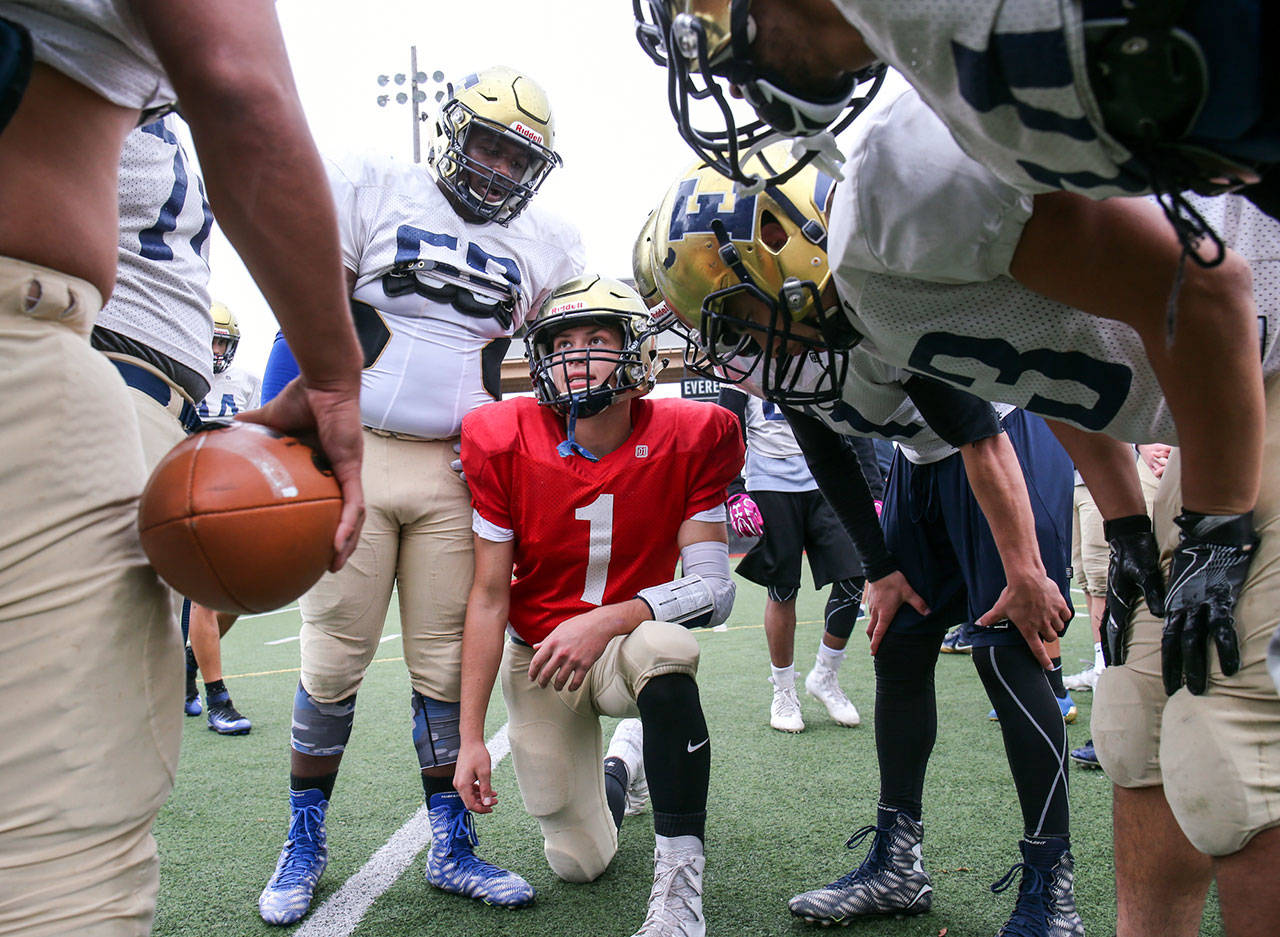 Everett quarterback Gabe Maggio (center) calls a play in a huddle during practice Oct. 18, 2017, at Everett Memorial Stadium. (Kevin Clark / The Herald)