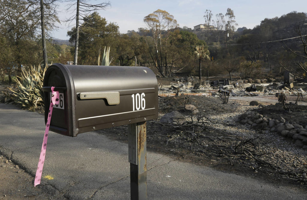In this Oct. 16 photo, a mailbox, one of few items left at the site of the destroyed home in Napa, where Sara and Charles Rippey died in a fast-moving wildfire, shows a pink and black polkadot ribbon that indicates a fire crew has visited the location. (AP Photo/Eric Risberg)
