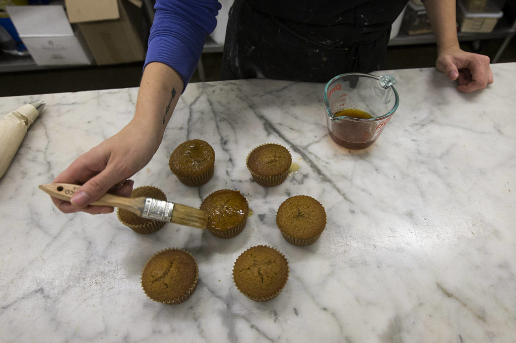 Lauren Anderson brushes beer on cupcakes. She’s not a beer drinker, but she smells the beer and talks to the brewers about the ingredients in it to figure out the best way to use it in baking. (Ian Terry / The Herald
