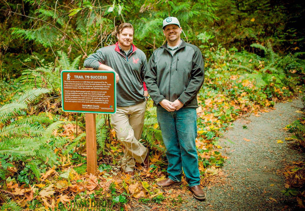 Jeb Bolton (in ballcap), a Snohomish County juvenile community corrections officer, and Matthew Wygant, a juvenile probation counselor, helped teens on a trail-building project at Kayak Point Regional Park. The joint program with the county parks department provides work experience and a paid stipend to young offenders from the Denney Juvenile Justice Center. (Snohomish County Parks Department)