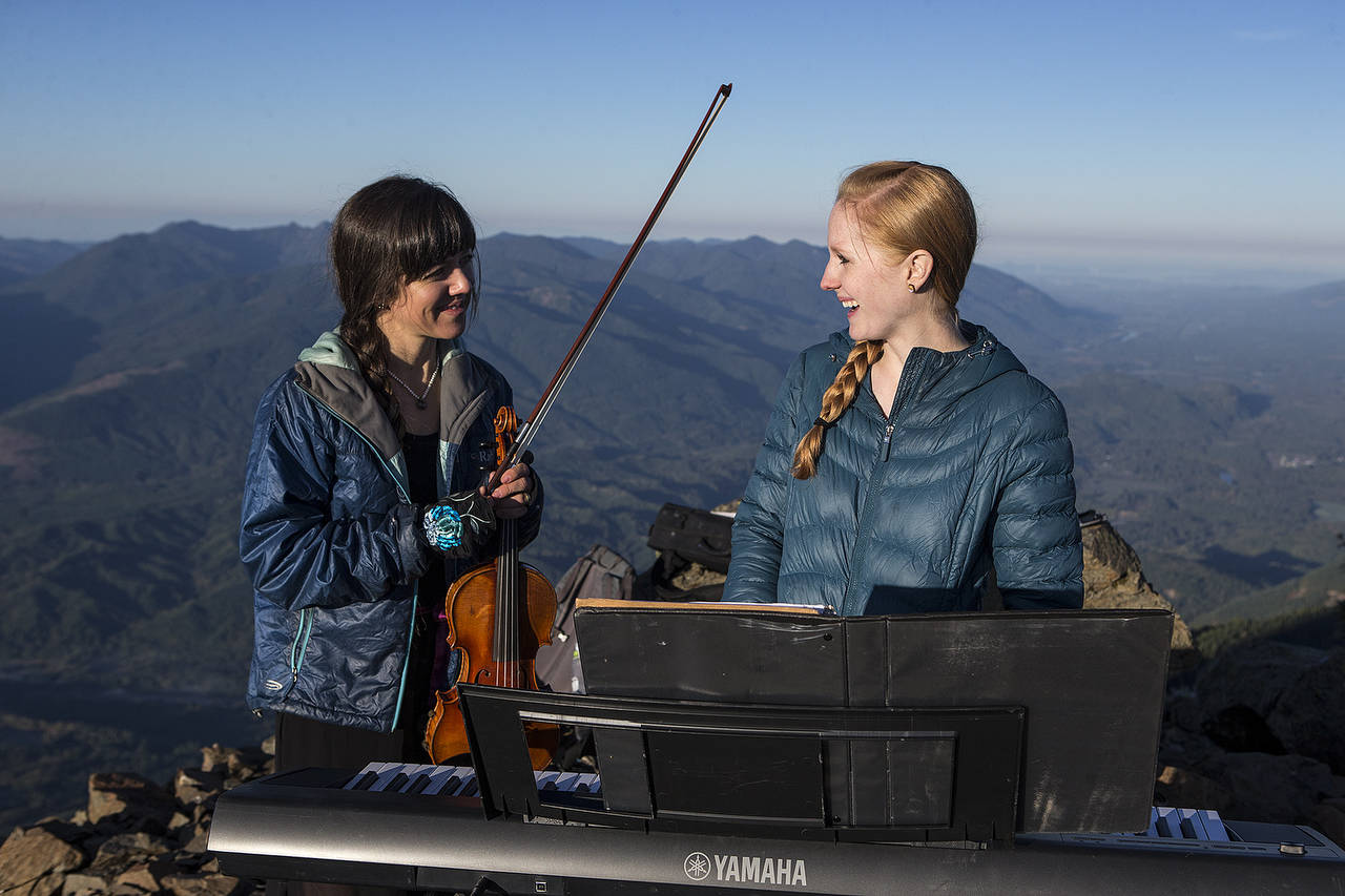 Anastasia Allison (left) and Rose Freeman laugh before playing at sunrise atop Sauk Mountain. (Ian Terry / The Herald)