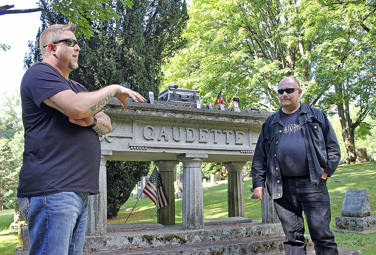 In this June 28 photo, Washington Abnormal Research Network (WARN) investigators Travis Fletcher (left) and Brian Lee explain how they use various devices to listen and watch for spirits or ghosts at Bay View Cemetery in Bellingham. (Kera Wanielista/Skagit Valley Herald via AP)