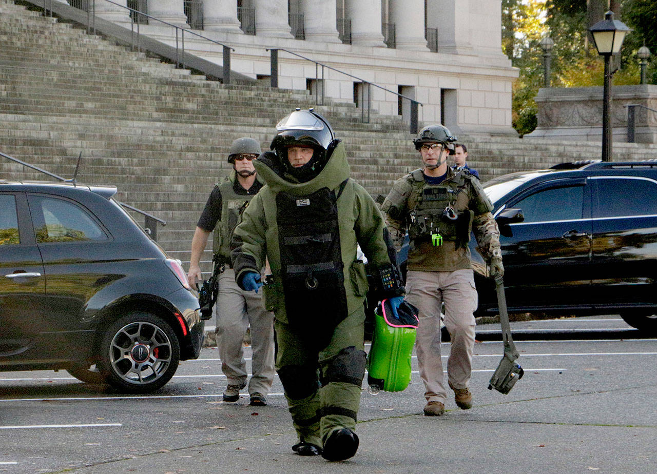 A member of the bomb squad carries a suitcase out of the Washington Capitol in Olympia on Monday. Washington Gov. Jay Inslee’s office was evacuated for a few hours after a woman dropped off the cartoon-themed suitcase, which she said was for the governor. (AP Photo/Rachel La Corte)