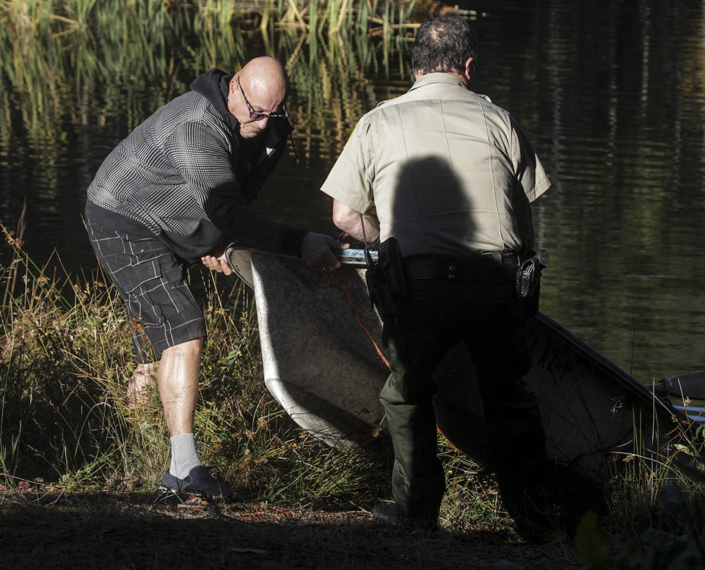 Jeffrey Abrams (left) pulls his dinghy ashore from King Lake on Tuesday. (Ian Terry / The Herald)
