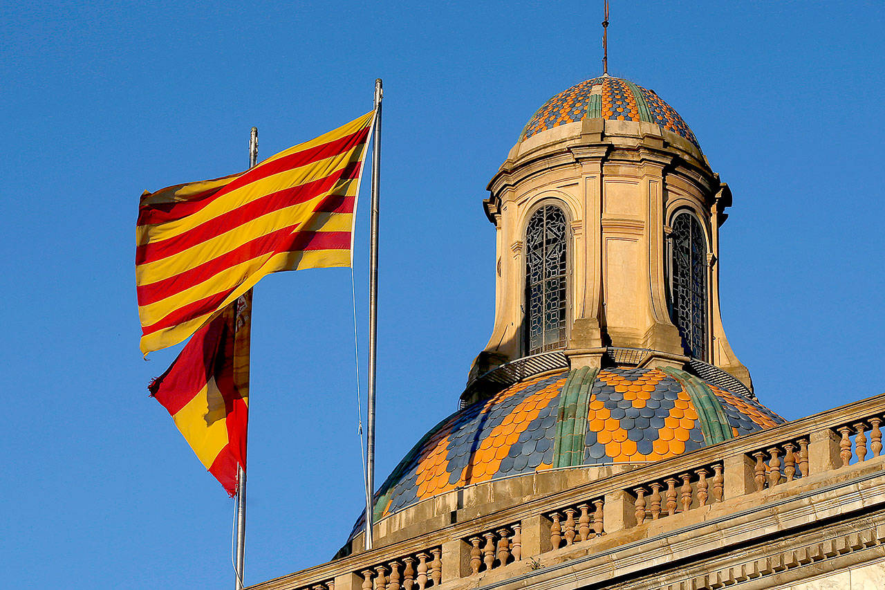 Catalan and Spanish flags flutter on top of the Palau Generalitat in Barcelona, Spain, early Monday. (AP Photo/Manu Fernandez)