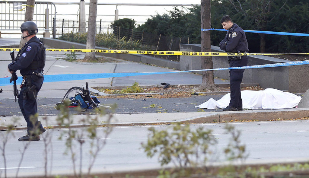 A New York Police Department officer stands next to a body covered under a white sheet near a mangled bike along a bike path Tuesday in New York. (AP Photo/Bebeto Matthews)
