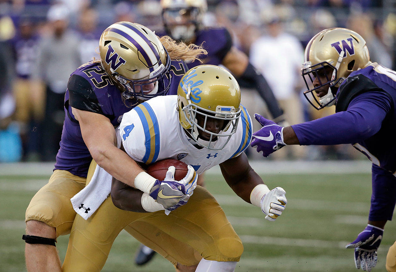 UCLA’s Bolu Olorunfunmi (4) is brought down by Washington’s Ben Burr-Kirven (25) and Jaylen Johnson in the first half of a game Oct. 28, 2017, in Seattle. (AP Photo/Elaine Thompson)