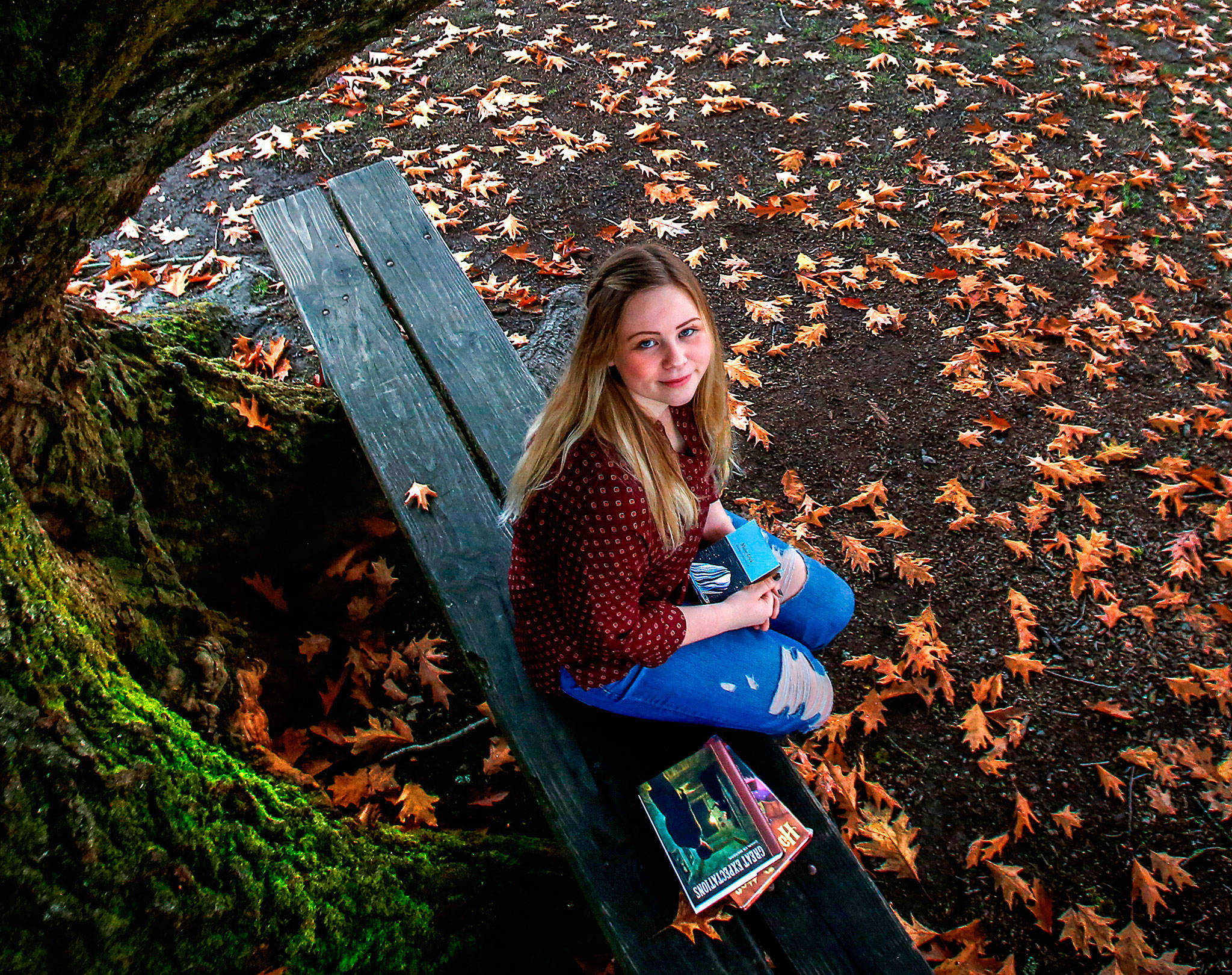 When Isabelle Strehle was in the fifth grade, her class at Dutch Hill Elementary raised money to help build a school in Kenya. They bought enough bricks to build one wall. Now as a senior at Snohomish High School, she is helping build a library and is collecting book donations. Beside her on the bench are “Harry Potter and the Sorcerer’s Stone” and “Great Expectations.” In her hands is the classic “Moby Dick.” (Dan Bates / The Herald)