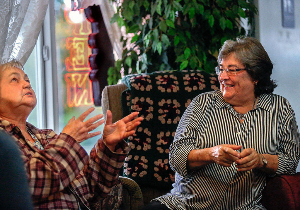 Shirley Lidel, 68 (left), shares some of her life with Executive Director Linda Paz, 69, in the Welcome Room at Matthew House, a hospitality center for prison families. Lidel’s husband, Michael, has been in prison for 14 years. (Dan Bates / The Herald)
