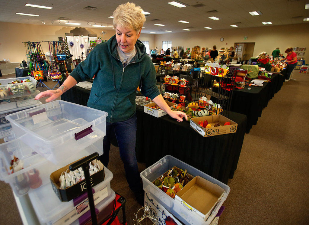 In a large multipurpose room above the Assistance League Thrift Store, volunteer Happi Favro sets up a table for the group to display and sell fundraising items early this November to help support Operation School Bell and other programs. (Dan Bates / The Herald)
