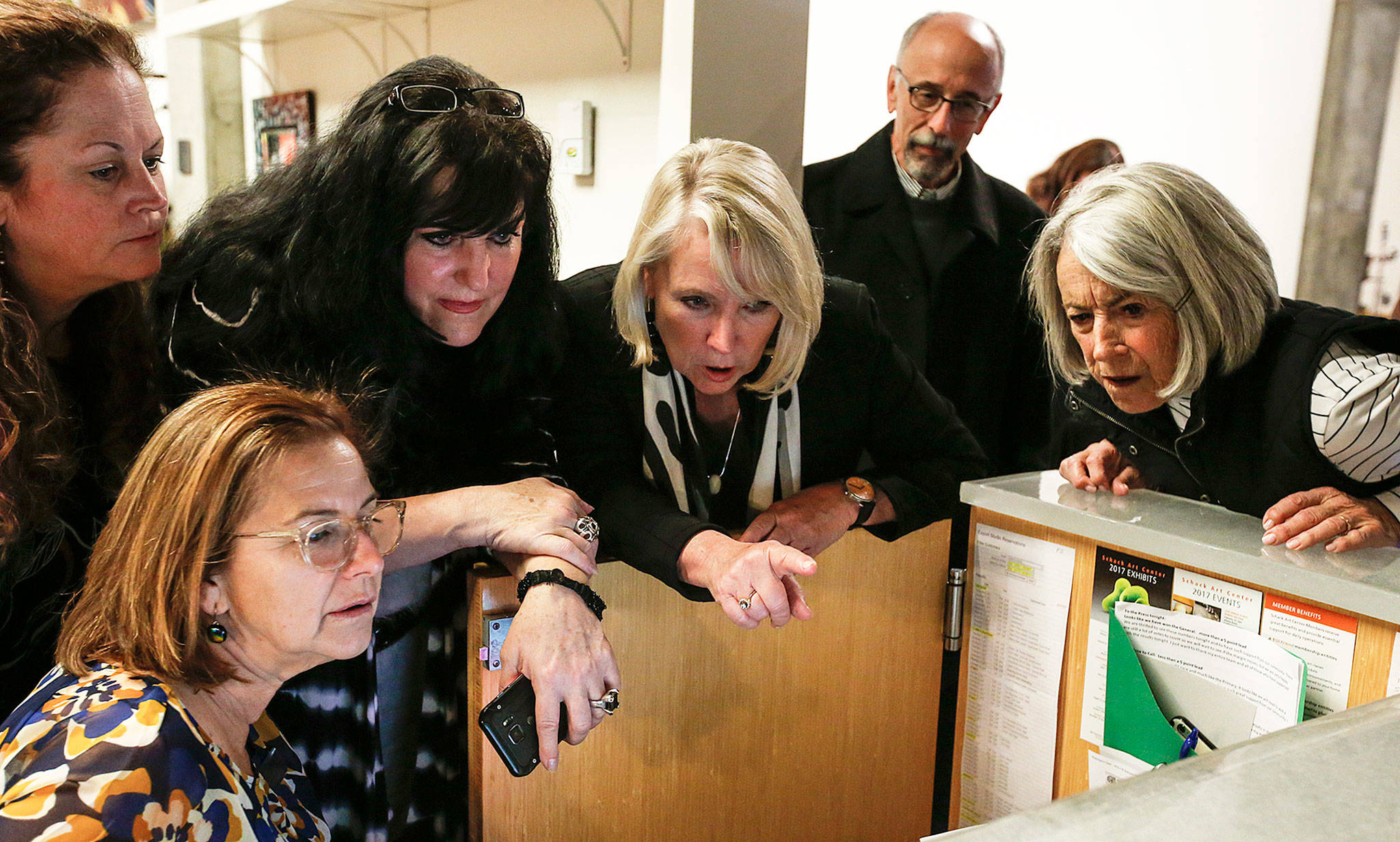 Judy Tuohy (center) looks over election results with supporters during a campaign party at Schack Art Center in downtown Everett on Tuesday. Initial results showed Tuohy with a narrow 49 vote lead over Cassie Franklin. (Ian Terry / The Herald)