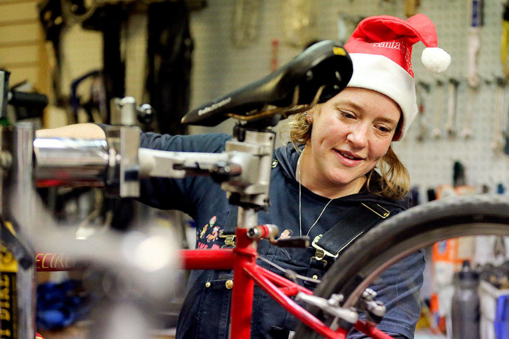 Sarah Molitch looks over bicycle under repair at Sharing Wheels in Everett on Nov. 5. (Kevin Clark / The Herald)
