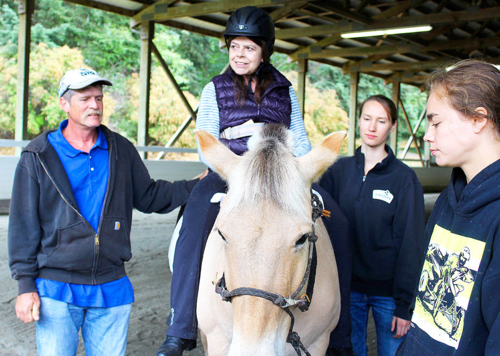 Smith is surrounded by volunteers with Equestrain Crossings while riding in the arena at Whidbey Equestrian Center. Greg Olde and Kellie Holden work as side walkers while Katie Locke (far right) leads the horse. (Patricia Guthrie/Whidbey News-Times)
