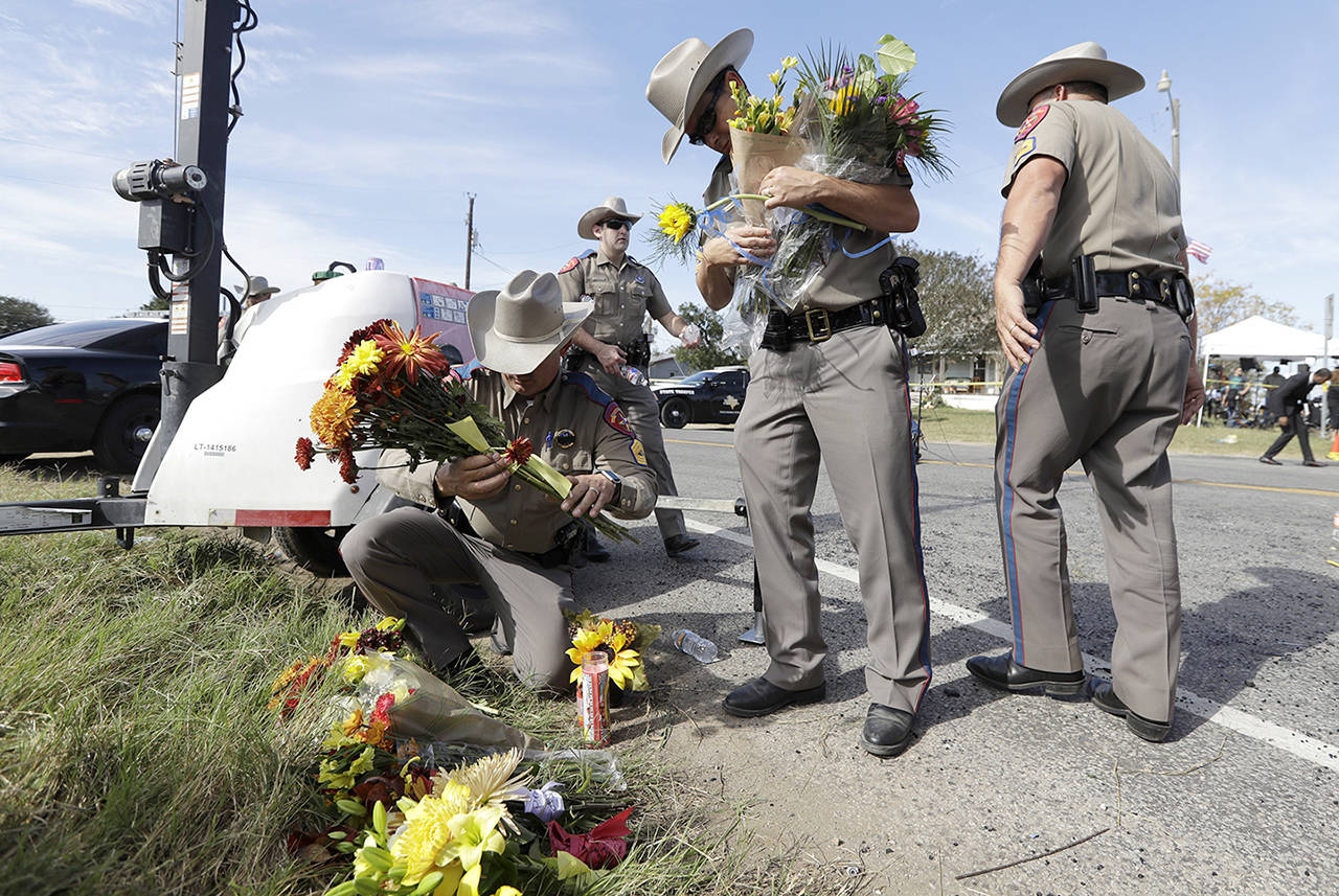 Law enforcement officials move flowers left at the scene of a shooting at the First Baptist Church of Sutherland Springs on Monday in Sutherland Springs, Texas. (AP Photo/Eric Gay)