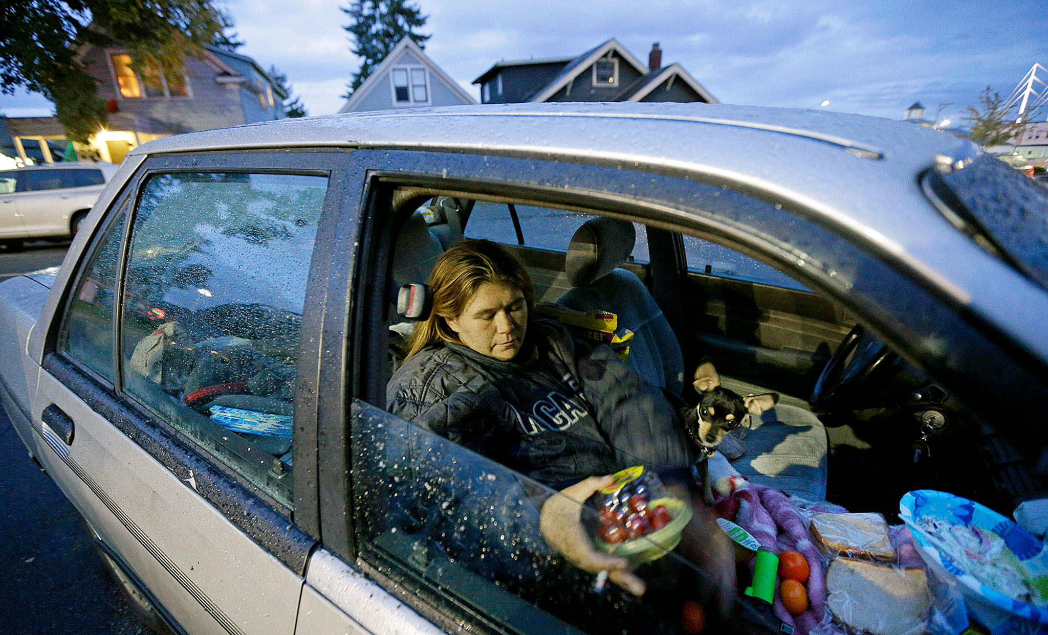 Paige Clem sits in the car she lives in with her husband and three dogs outside a church in Everett, where free food was being distributed. Clem, who said she has battled drug addiction in the past but was now clean, said having enough money just to run the heat in her car and move it when required was a daily challenge. (AP Photo/Ted S. Warren)