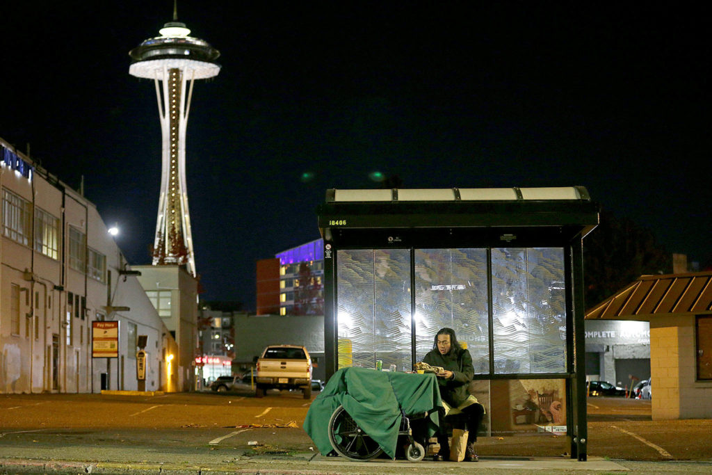 Dave Chung, who says he has been homeless for five years on the streets of California and Washington, eats a meal before bedding down in a bus shelter in view of the Space Needle in Seattle. Chung says he has been offered shelter many times, but chooses to remain outside due to the living conditions in homeless shelters and conflicts he has with other people. (AP Photo/Ted S. Warren) 
