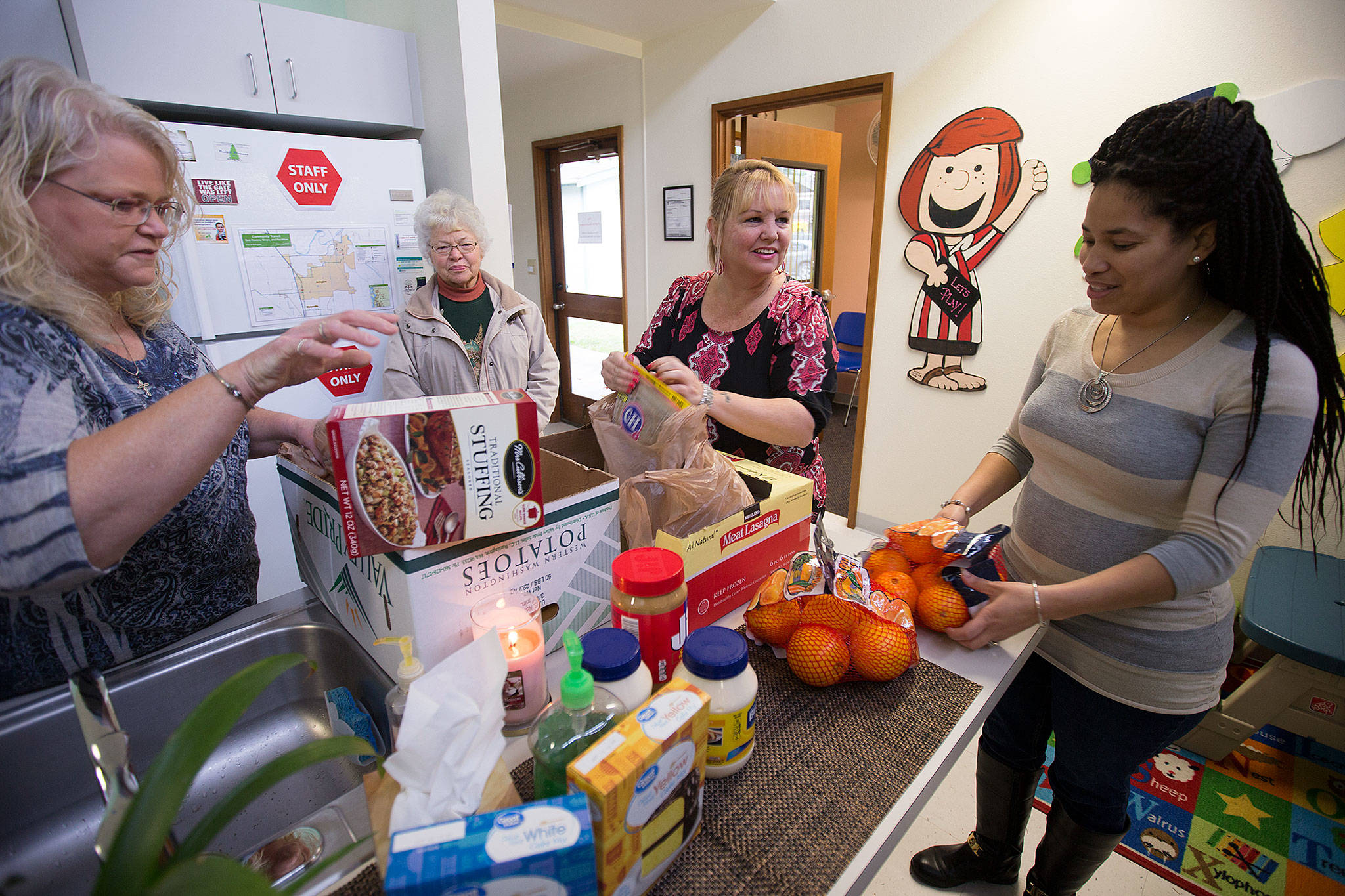 Peggy Ray (center), Tracey Nelson (left) and Doris Drohin (right) organize food brought in by Jeannie Lish (background) at the Arlington Community Resource Center on Nov. 20. Ray began the center in the aftermath of the Oso mudslide and now oversees six family centers in Snohomish County. (Andy Bronson / The Herald)