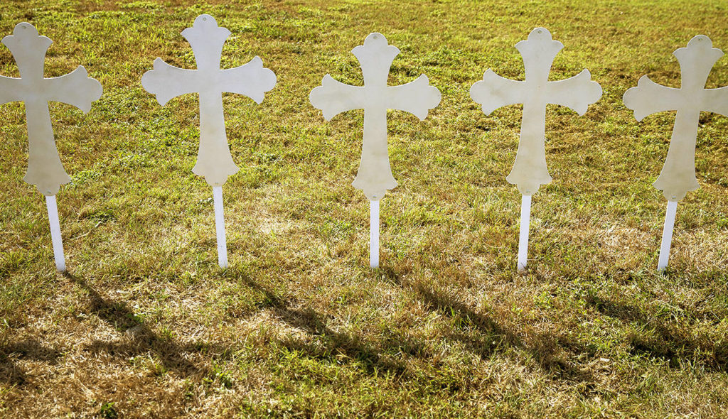 Twenty-six crosses cast shadows in a grassy area of a gas station next to TX-87 in Sutherland Springs, Texas, on Monday. The crosses were erected by four community members in memory of those killed during a Sunday service at the Sutherland Springs First Baptist Church. (Nick Wagner/Austin American-Statesman via AP)

