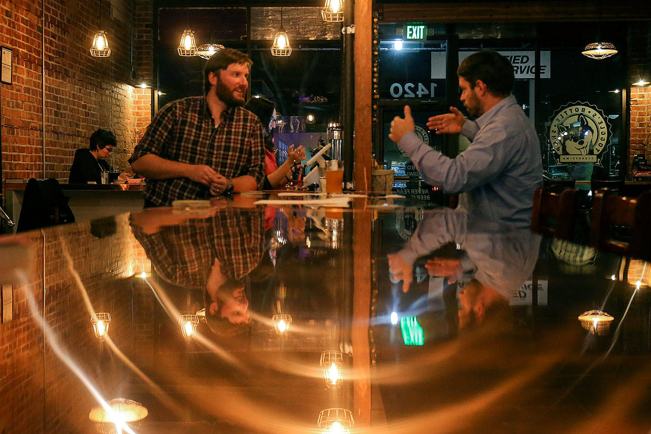 Co-owner Colin Lothrop (left) talks with Sean Curran Wednesday at Toggle’s Bottleshop in Everett. (Kevin Clark / The Herald)