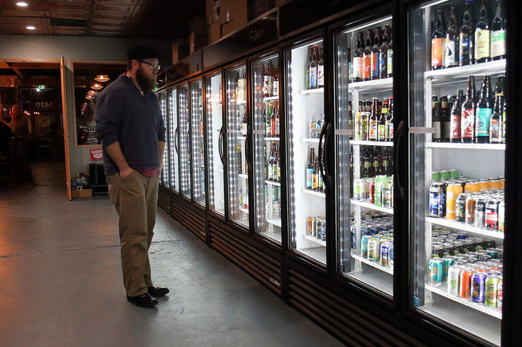 Daniel Howe browses the more than 550 different beers available at Toggle’s. (Kevin Clark / The Herald)
