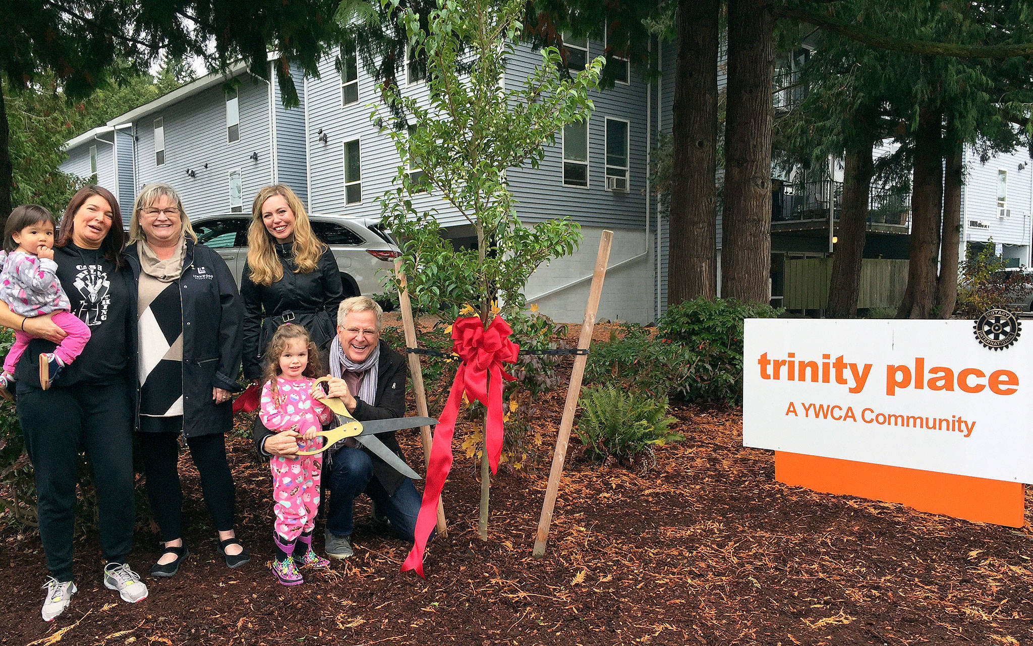 Rick Steves (right) at Trinity Place, the Lynnwood property he donated this year to YWCA Snohomish County. He was joined by (from left) Trinity Place resident Ricanna (holding child), Lynnwood Mayor Nicola Smith and YWCA Executive Director Mary Anne Dillon. (Contributed photo)