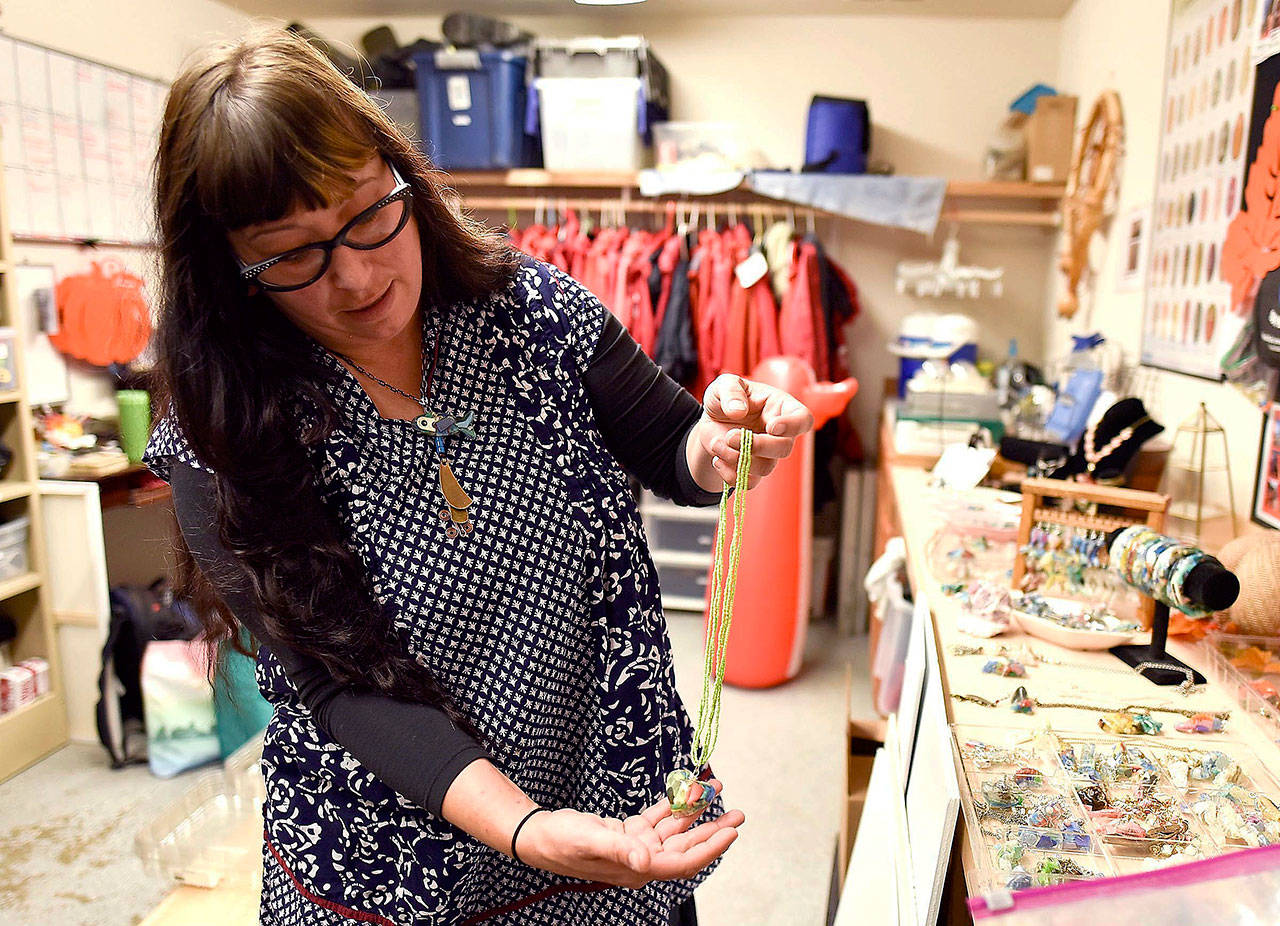 Pooka Rice, outreach coordinator with the Haystack Rock Awareness Program, on Wednesday shows off jewelry made with pieces of plastic debris removed from local beaches near Cannon Beach, Oregon. (Colin Murphey / Daily Astorian)