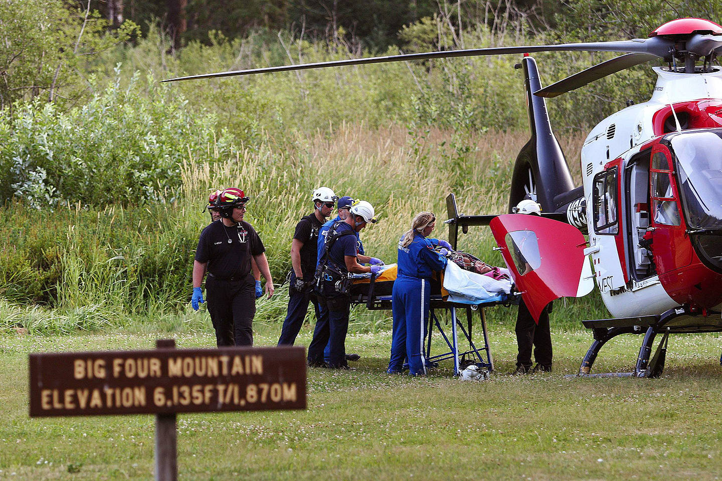 Rescue workers treat a survivor before she is airlifted, July 6, 2015, at the Big Four Ice Caves trailhead east of Verlot. Two other people died from injuries sustained in the collapse. Frontier Communications is considering removing a payphone at the Verlot ranger station, which could increase response time to similar emergencies. (Genna Martin / Herald file photo)