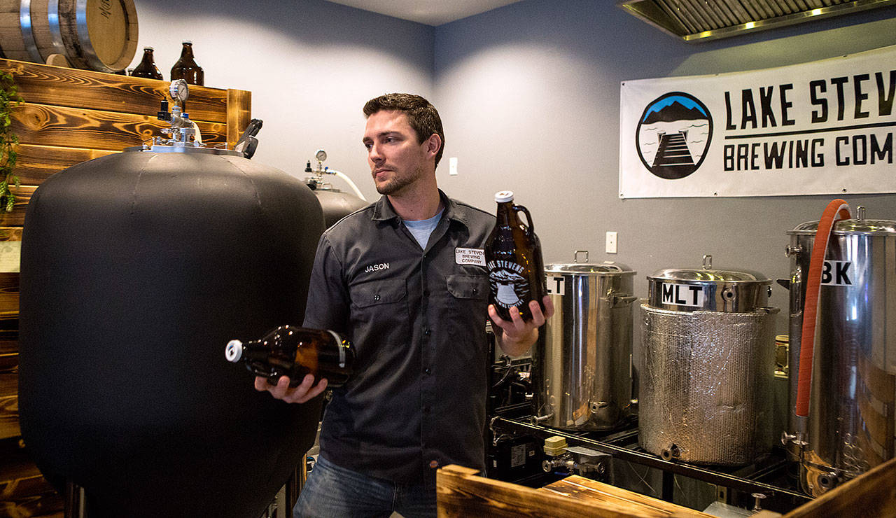 Co-owner Jason Parzyk carries two growlers to fill as he serves up beer at Lake Stevens Brewing Co. The first brewery in the city is celebrating one-year anniversary this weekend. (Andy Bronson / The Herald)