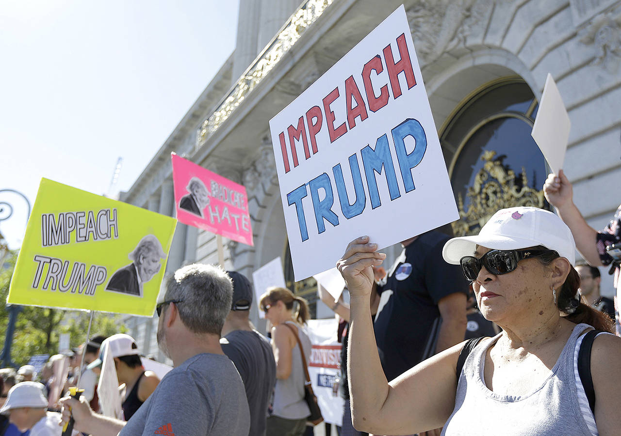 People hold up signs at a rally calling for the impeachment of President Donald Trump in San Francisco on Oct. 24. (AP Photo/Jeff Chiu)